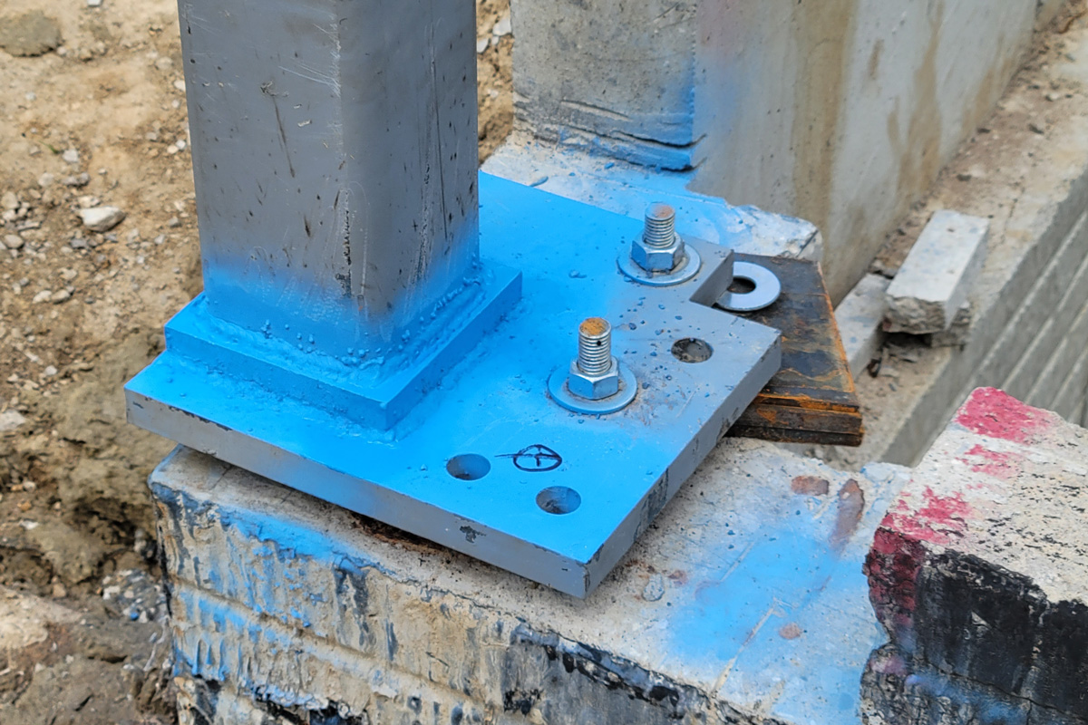construction-base-plate picture of a steel column base plate with anchor bolts and washers on a concrete foundation